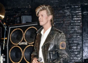 David Bowie con chaqueta de cuero y micrófono en el escenario durante su época de rock clásico