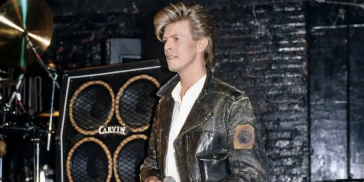 David Bowie con chaqueta de cuero y micrófono en el escenario durante su época de rock clásico